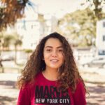 Smiling young woman enjoying a sunny day outdoors, showcasing casual fashion and happiness.